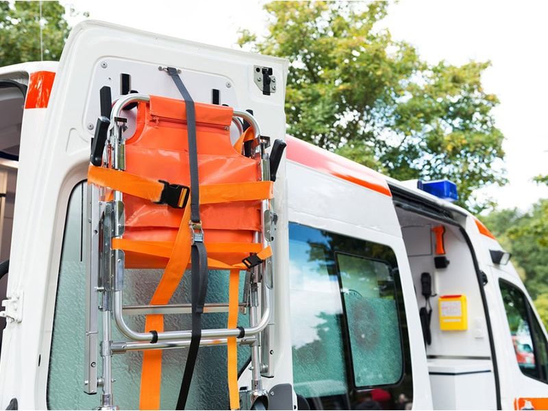 Foldable emergency stretcher securely mounted on the door of an ambulance, ready for rapid deployment.
