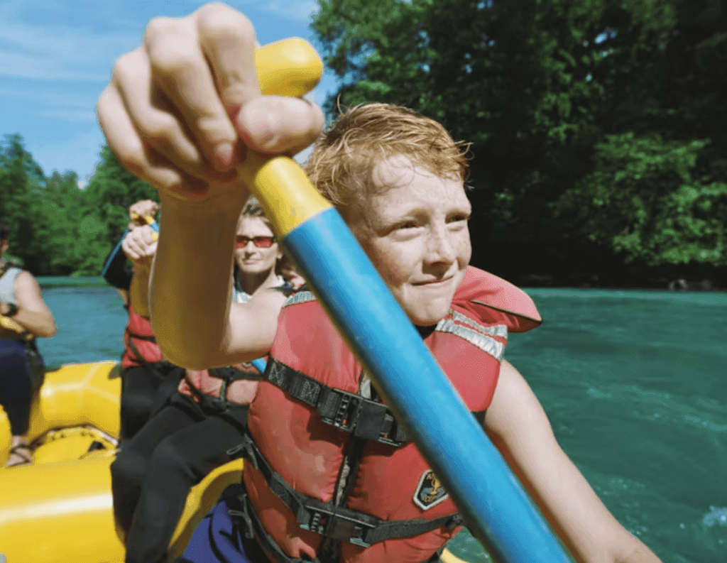 Children Rafting on River Wearing Life Jackets